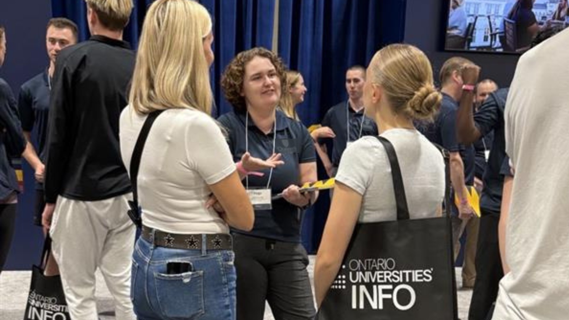 A mom and daughter talking to a university rep at a Regional Fair